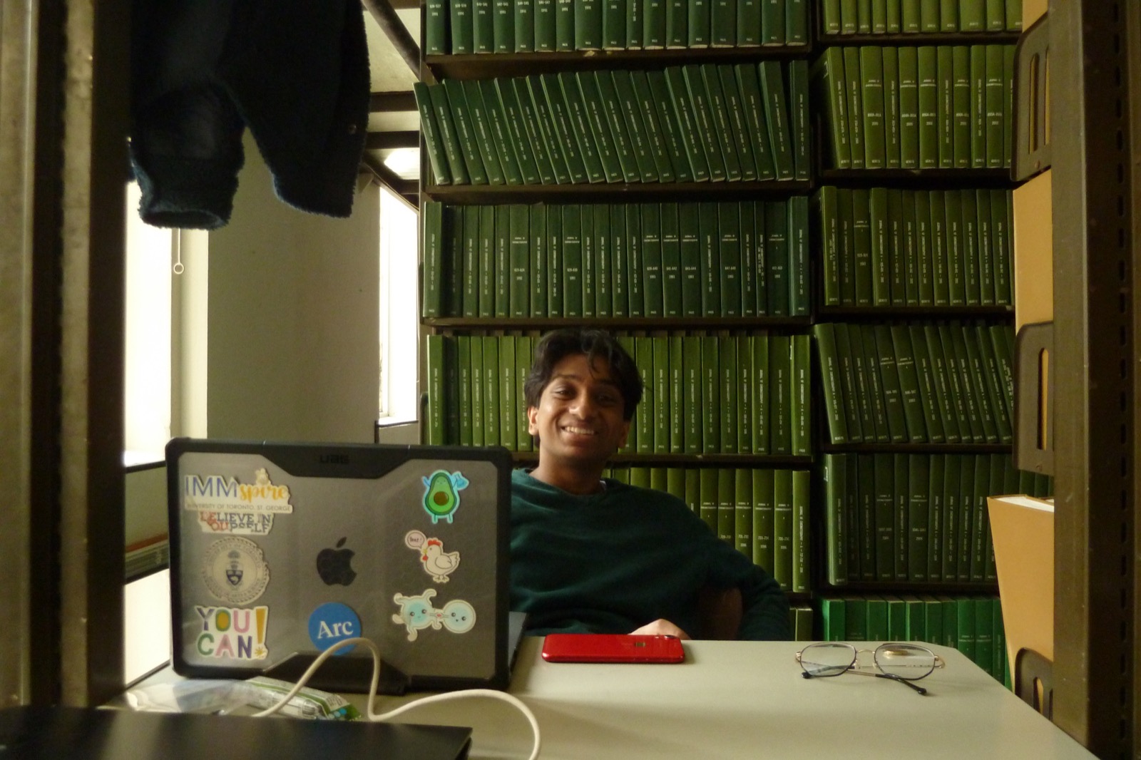 Sid smiling at a laptop in a library workspace
